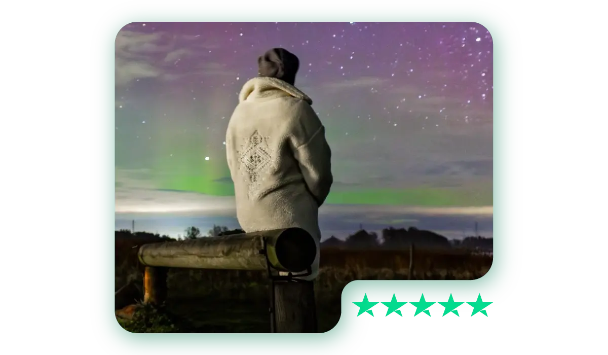 A photo of a person in a warm coat watching the Northern Lights under a starry sky, with a Trustpilot 5-star rating graphic in the corner.